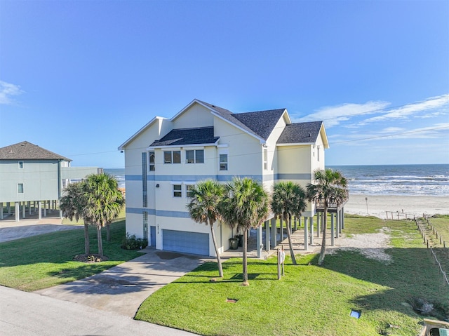 view of front facade featuring a front yard, a garage, a beach view, and a water view