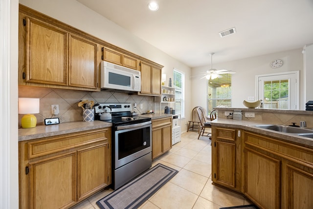 kitchen featuring decorative backsplash, a wealth of natural light, ceiling fan, and stainless steel range with electric cooktop