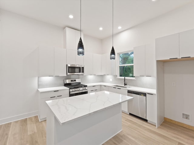 kitchen featuring white cabinetry, a kitchen island, decorative light fixtures, and appliances with stainless steel finishes