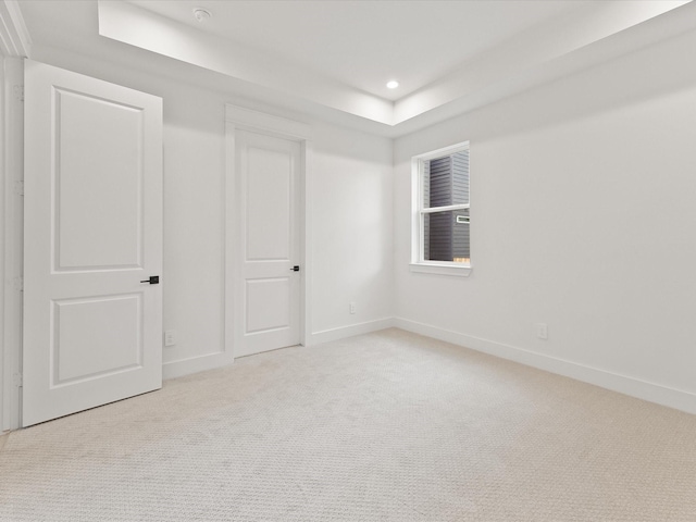 unfurnished room featuring a tray ceiling and light colored carpet