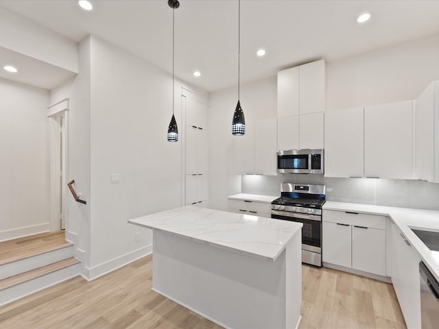 kitchen featuring appliances with stainless steel finishes, a center island, white cabinetry, and pendant lighting