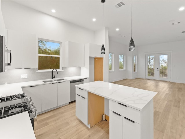 kitchen featuring white cabinetry, a center island, sink, dishwasher, and pendant lighting