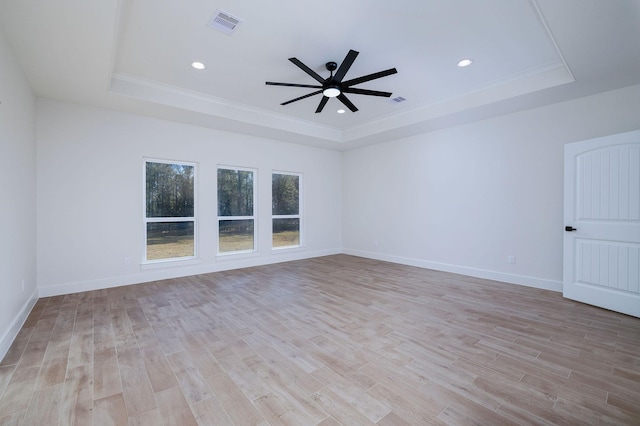 unfurnished room with light wood-type flooring, a raised ceiling, ceiling fan, and crown molding