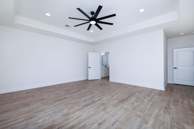 spare room with ceiling fan, ornamental molding, light hardwood / wood-style flooring, and a tray ceiling