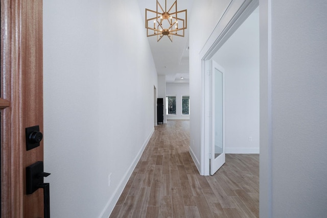 hallway with a notable chandelier and light hardwood / wood-style floors