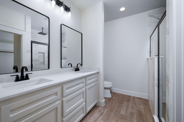 bathroom featuring a shower with door, vanity, and toilet