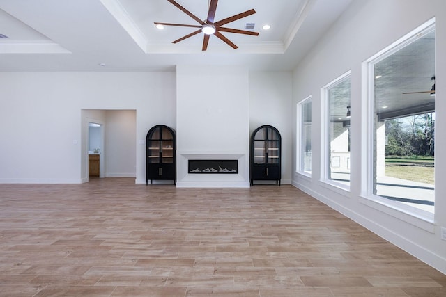 unfurnished living room with a tray ceiling, ceiling fan, and light hardwood / wood-style floors