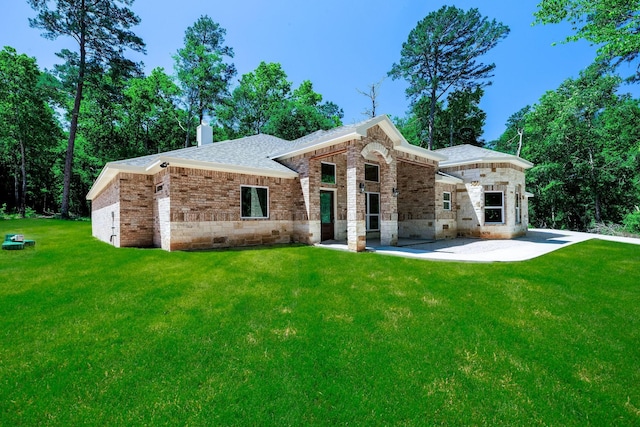 228 Feldspar Ln, Huntsville, TX 77340 - rear view of property with a patio area, a shingled roof, a yard, a chimney, and brick siding