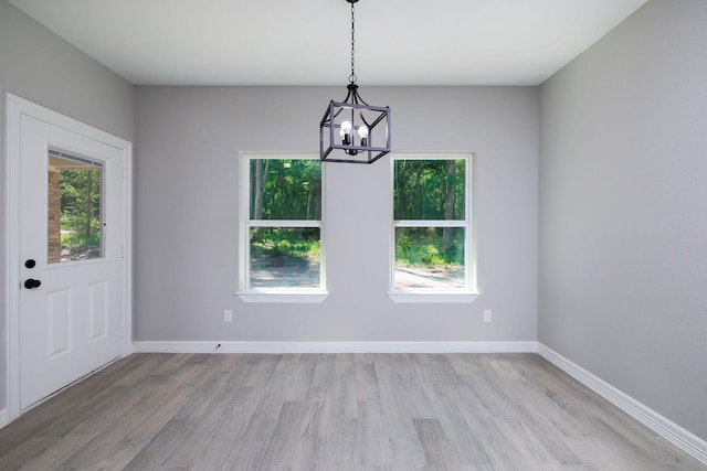 228 Feldspar Ln, Huntsville, TX 77340 - unfurnished dining area with healthy amount of natural light, a chandelier, light wood-type flooring, and baseboards