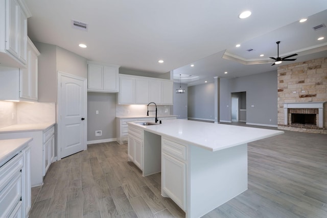 228 Feldspar Ln, Huntsville, TX 77340 - kitchen with a sink, a ceiling fan, a kitchen island with sink, light wood-style floors, and white cabinetry