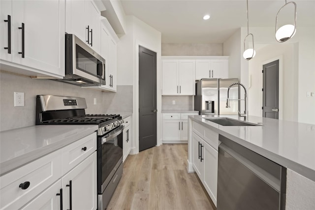 kitchen featuring white cabinets, sink, stainless steel appliances, and hanging light fixtures