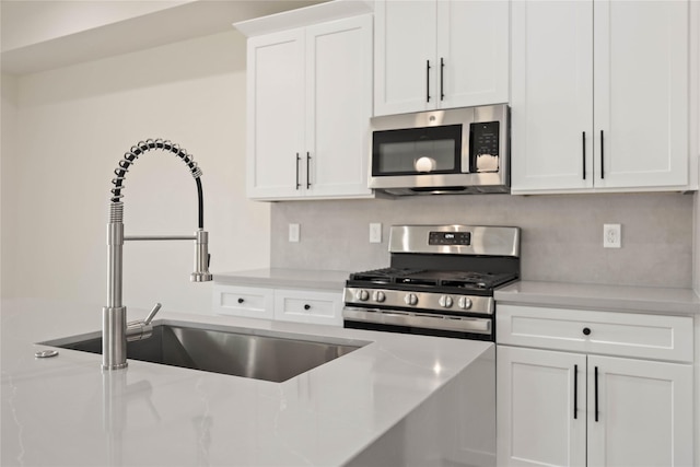 kitchen featuring backsplash, white cabinets, sink, light stone counters, and stainless steel appliances