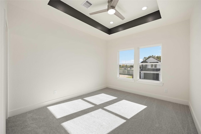 carpeted spare room with ceiling fan and a tray ceiling