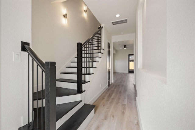 staircase with ceiling fan and hardwood / wood-style floors