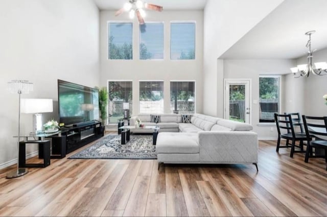 living room featuring a towering ceiling, ceiling fan with notable chandelier, and hardwood / wood-style flooring