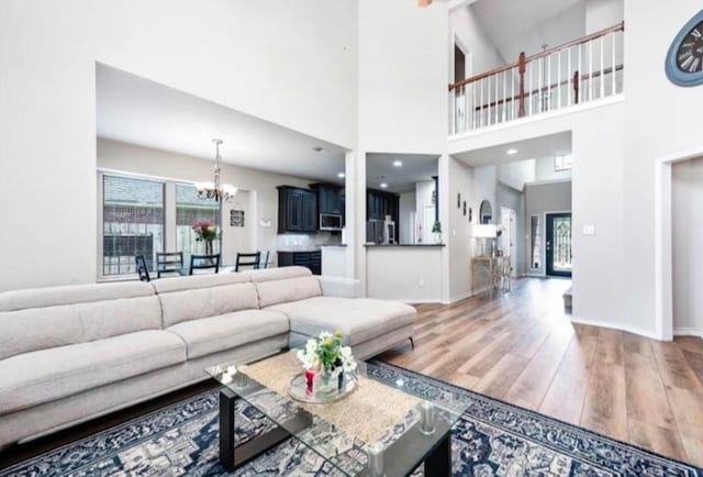 living room featuring a chandelier, wood-type flooring, and a high ceiling