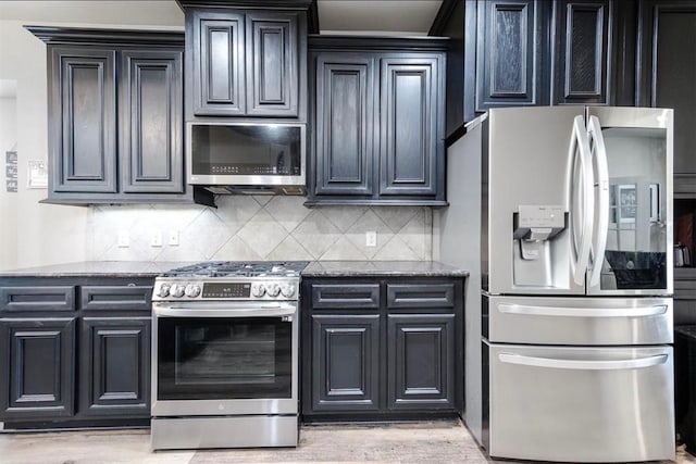 kitchen with decorative backsplash, stainless steel appliances, light hardwood / wood-style flooring, and dark stone countertops