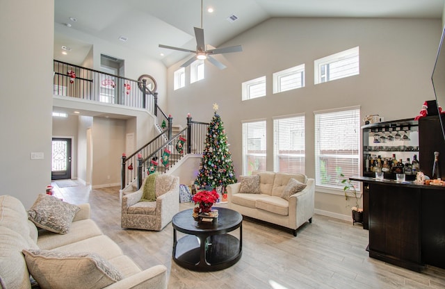 living room featuring bar, a high ceiling, light hardwood / wood-style floors, and ceiling fan