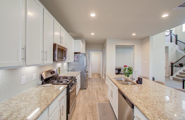 kitchen featuring appliances with stainless steel finishes, white cabinetry, and light stone counters