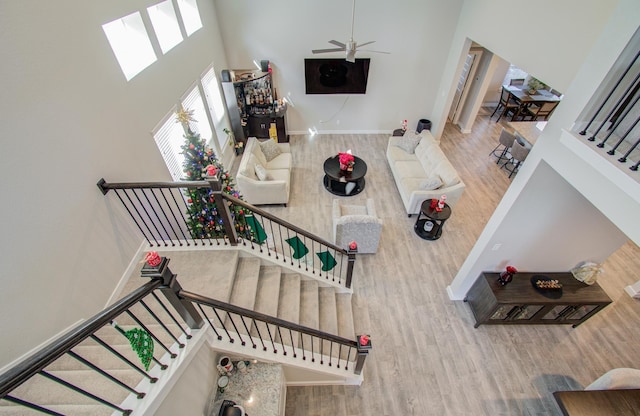 living room featuring a high ceiling, a skylight, hardwood / wood-style flooring, and ceiling fan