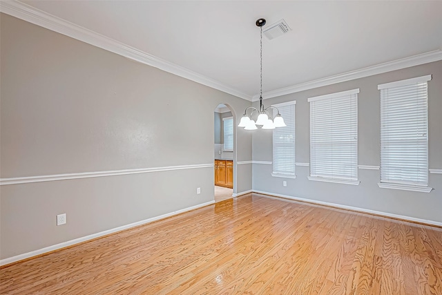 spare room featuring a chandelier, light wood-type flooring, and ornamental molding