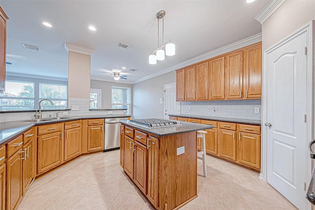 kitchen with appliances with stainless steel finishes, ceiling fan, sink, a center island, and hanging light fixtures