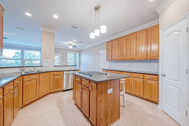 kitchen featuring a kitchen bar, stainless steel appliances, sink, a kitchen island, and hanging light fixtures