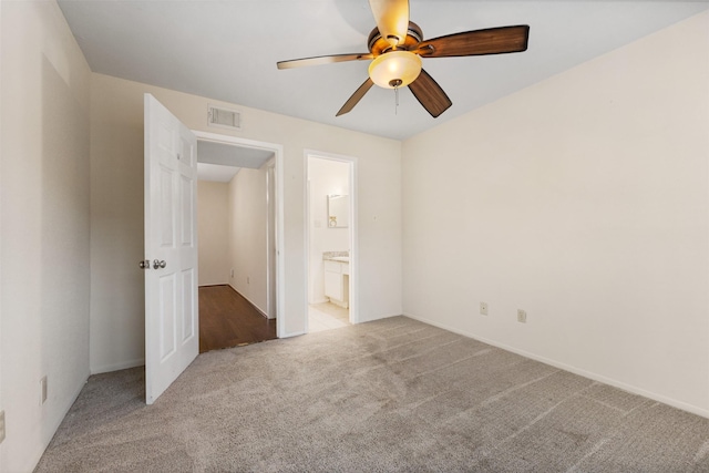 unfurnished bedroom featuring ensuite bathroom, ceiling fan, and light colored carpet