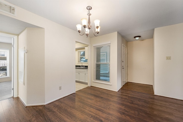 empty room featuring a chandelier and dark hardwood / wood-style floors