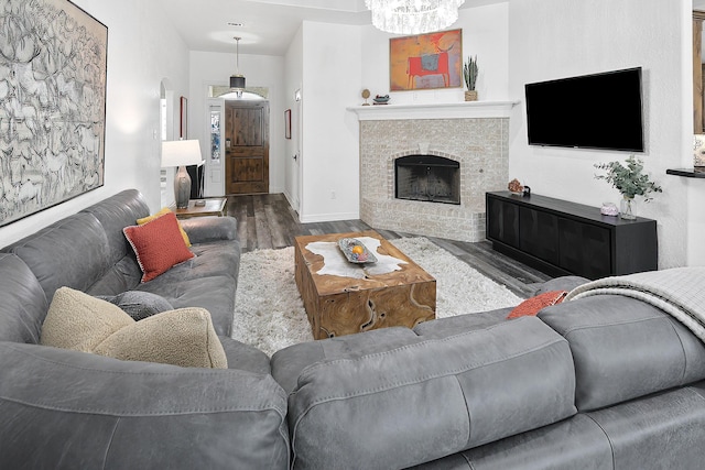 living room featuring a fireplace, dark wood-type flooring, and an inviting chandelier