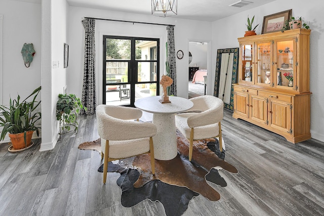 dining space featuring french doors, wood-type flooring, and a notable chandelier