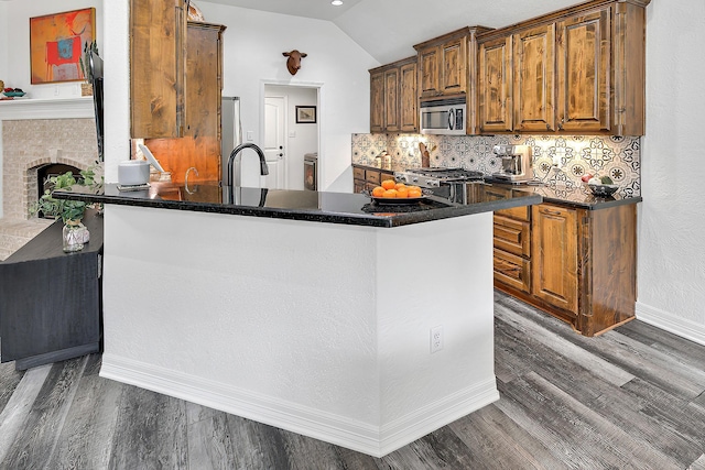 kitchen with stove, kitchen peninsula, dark wood-type flooring, and vaulted ceiling