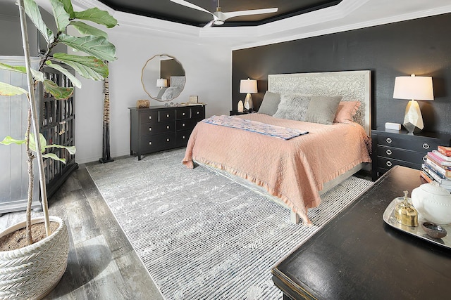 bedroom with wood-type flooring, a tray ceiling, ceiling fan, and ornamental molding