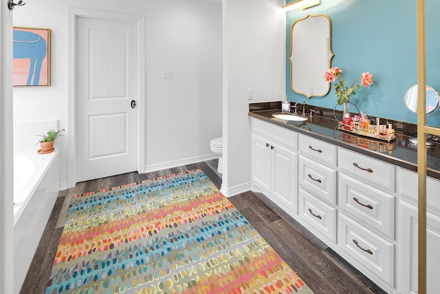 bathroom featuring vanity, toilet, wood-type flooring, and a tub