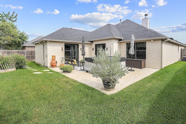 back of property with a lawn, a patio, and a hot tub