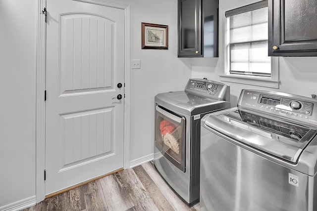 washroom featuring cabinets, hardwood / wood-style floors, and washer and clothes dryer