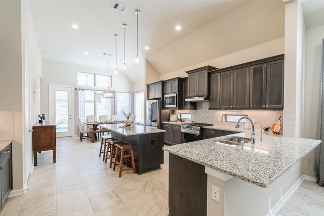 29614 Sterling Knoll Dr, Fulshear, TX 77441 - kitchen with backsplash, appliances with stainless steel finishes, a sink, light stone counters, and a breakfast bar