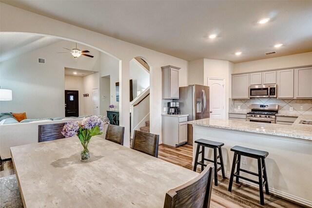 dining room featuring ceiling fan, light wood-type flooring, and lofted ceiling