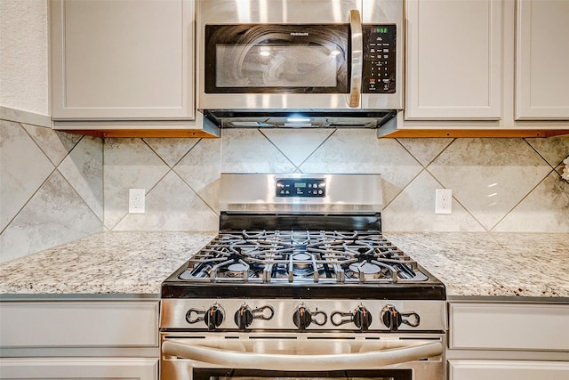 kitchen featuring backsplash, light stone countertops, and stainless steel appliances