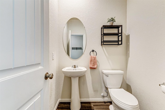 bathroom with wood finished floors, toilet, and baseboards