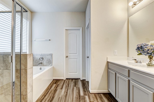 bathroom with vanity, wood finished floors, a bath, and baseboards