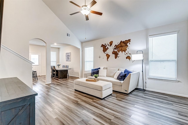 living room with arched walkways, plenty of natural light, wood finished floors, and visible vents