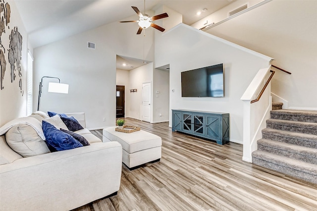 living area featuring light wood finished floors, ceiling fan, stairs, and visible vents