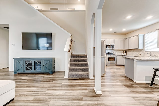 kitchen with light wood-type flooring, white cabinetry, stainless steel appliances, and open floor plan