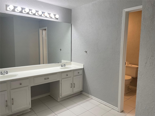 bathroom with a textured ceiling, tile patterned flooring, vanity, and toilet