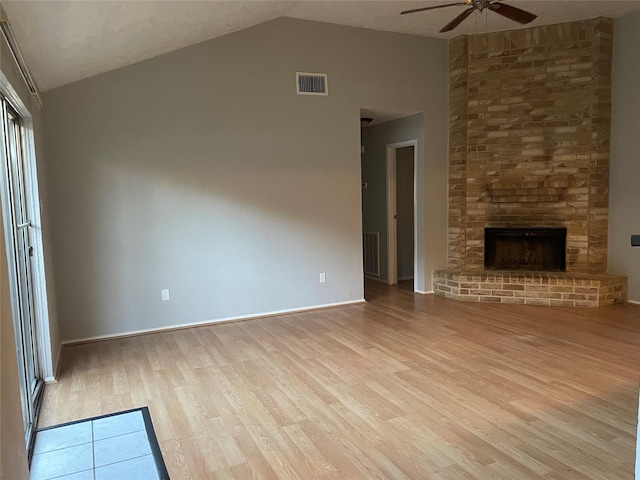 unfurnished living room with a large fireplace, ceiling fan, light wood-type flooring, and vaulted ceiling