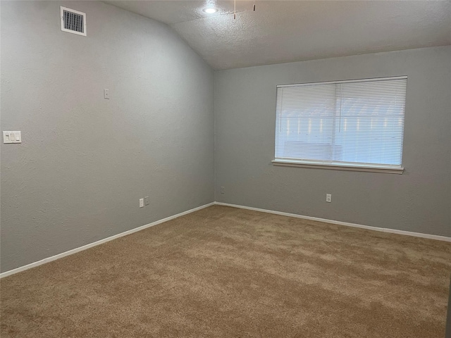 carpeted spare room featuring a textured ceiling and vaulted ceiling