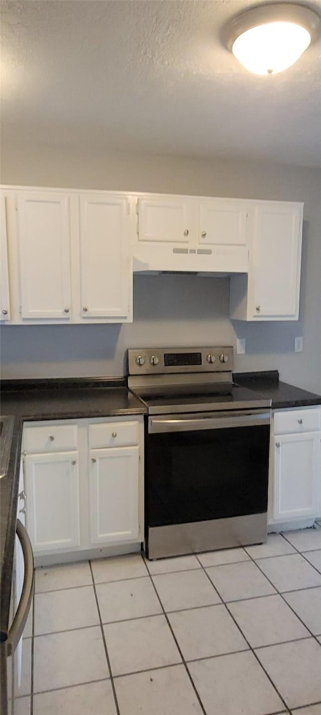 kitchen with a textured ceiling, stainless steel range with electric cooktop, light tile patterned flooring, and white cabinetry