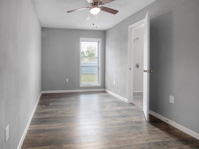 empty room with ceiling fan and dark hardwood / wood-style flooring