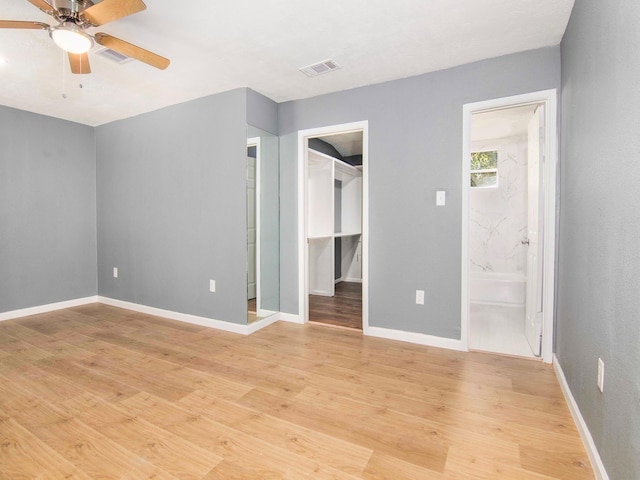 unfurnished bedroom with light hardwood / wood-style floors, ensuite bathroom, ceiling fan, and a spacious closet